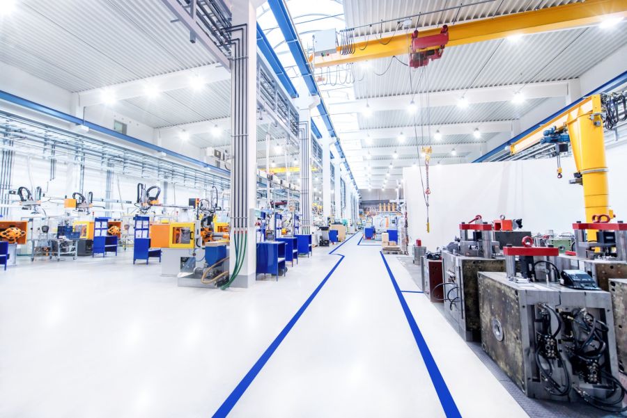 Clean industrial manufacturing facility with machinery, overhead cranes, and polished floors